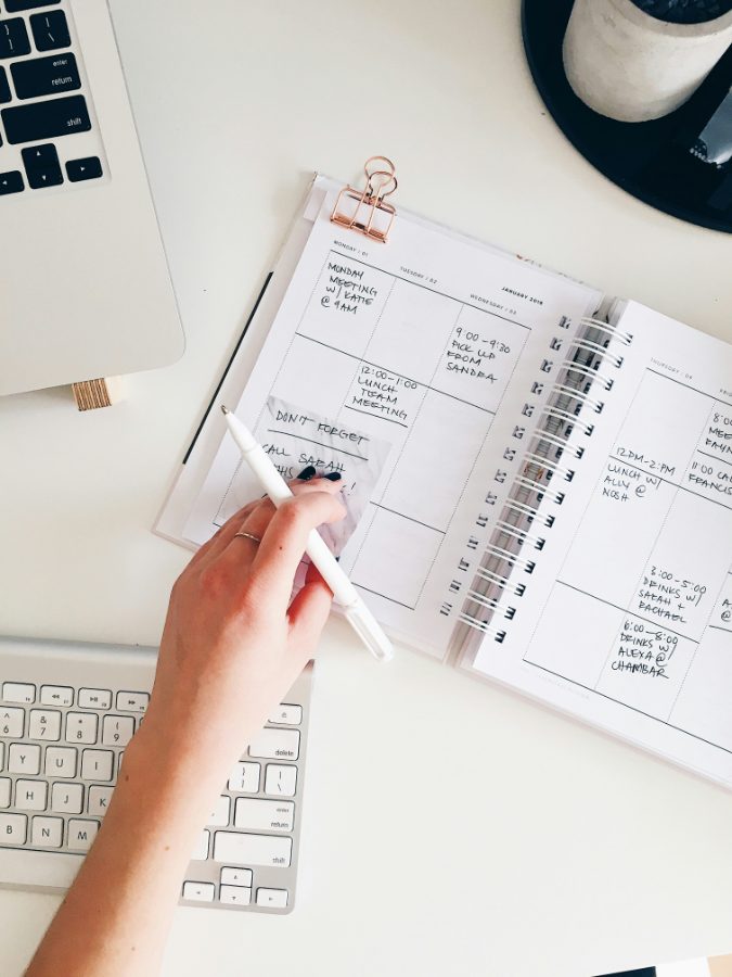 A week-to-view planner filled in by hand beside a laptop and keyboard